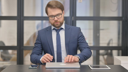 Young Businessman Coming and Opening Laptop to Workの写真素材