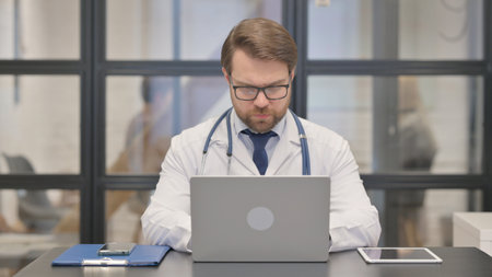 Doctor Typing on Laptop in Hospital