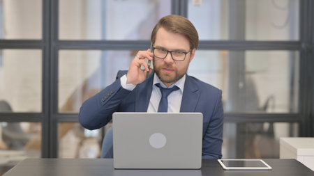 Young Businessman Talking on Phone at Work