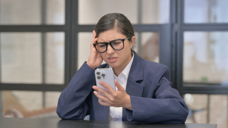 Mixed Race Businesswoman Criticizing Loss on Phoneの写真素材