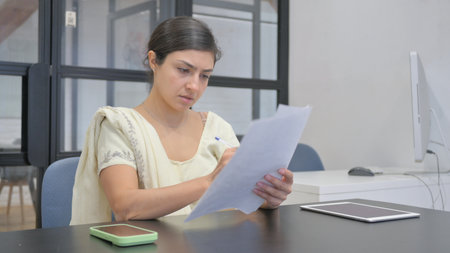 Indian Woman Reading Documents in Officeの写真素材
