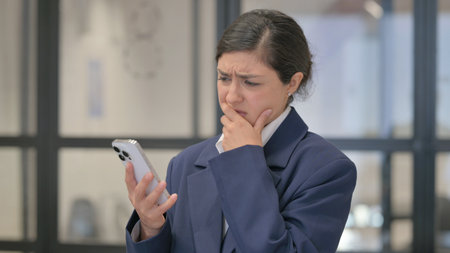 Portrait of Indian Businesswoman Criticizing Online Loss on Phoneの写真素材