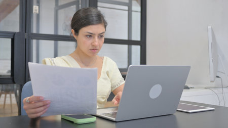 Indian Woman Working on Documents and Laptopの写真素材
