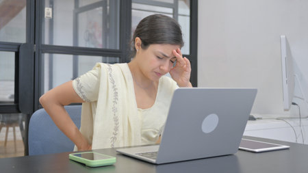 Indian Woman with Spinal Injury having Back Pain at Workの写真素材