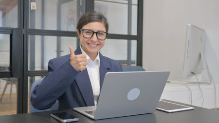 Thumbs Up by Indian Businesswoman Working on Laptopの写真素材