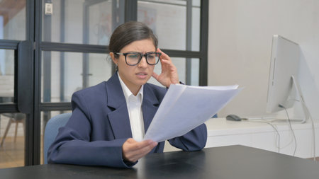 Pessimistic Indian Businesswoman Upset while Reading Business Reportの写真素材