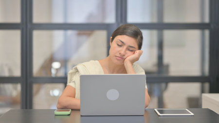 Tired Young Indian Woman Sleeping in front of Laptop