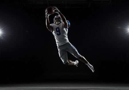 American football player in action, isolated on black background. Studio shot.の素材