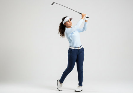 Full length portrait of a happy woman playing golf isolated on a white backgroundの素材