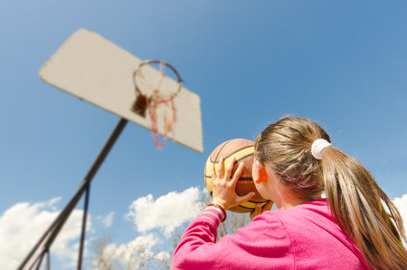 beautiful girl shooting basket and playing basketball, lower view wide angleの写真素材