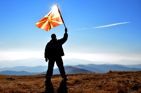 successfull silhouette man winner waving Macedonian flag on top of the mountain peakの写真素材