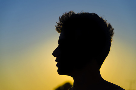 handsome boy silhouette portrait on colorful sunset clear skyの写真素材
