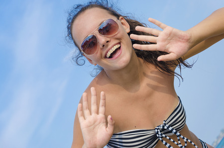 Close-up of a young teen girl in bikini with glasess looking surprised against blue skyの写真素材