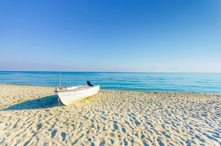 Boat on empty sea beach and horizon at sunriseの写真素材