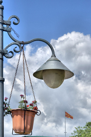 Candelabre and flower holder on the post, macedonia flag waving at the backの写真素材