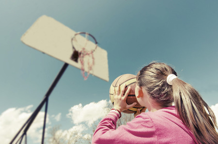 beautiful girl shooting basket and playing basketball, lower view wide angleの写真素材