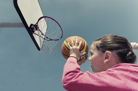 beautifull girl shooting basket and playing basketball, lower view wide angleの写真素材