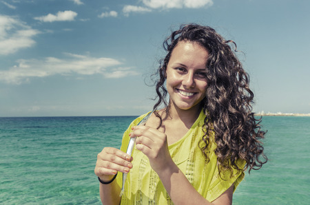 Happy fisherman girl loves fish. Beautiful girl holding fish on nice clear water blue sky horizon. Dressed in an contrast clothes, curly hairの写真素材