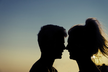 romantic couple silhouette profiles at sunset express love touching noses. Backlit emotionの写真素材