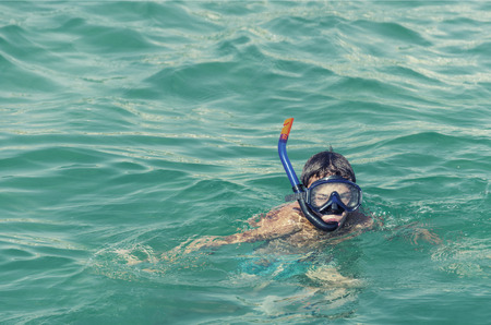 Boy in snorkeling mask with snorkel at sea, ocean green waterの写真素材
