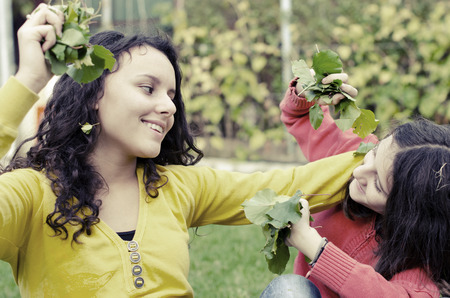 two beautiful  happy kids playing with leafs in gardenの写真素材