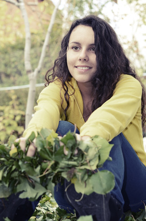 beautiful yellow shirt girl teenager relaxing happy in the garden holding green leafsの写真素材