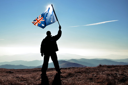 successfull silhouette man winner waving Australian flag on top of the mountain peakの写真素材