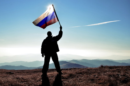 successfull silhouette man winner waving Russian flag on top of the mountain peakの写真素材