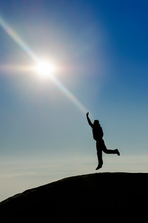 Silhouette of a champion on the high mountain reaching the sun. の写真素材