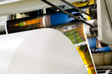 A large webset offset printing press running a long roll off paper over its rollers at high speed.の写真素材