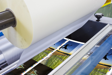 offset machine press print run at table, sheet-fed paper feeder unit. Poster laminator