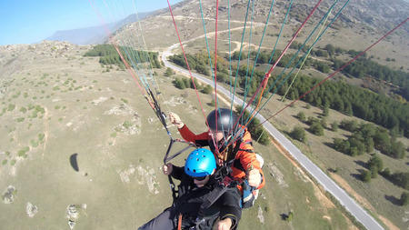 Tourist playing paragliding guided by a pilotの写真素材