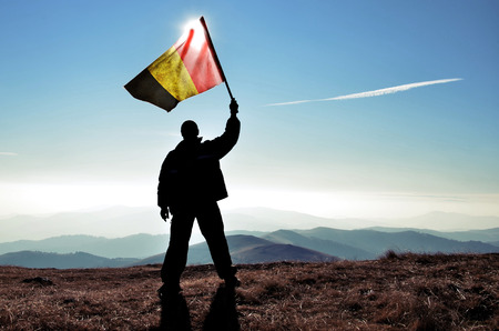 successful silhouette man winner waving Belgium flag on top of the mountain peakの写真素材