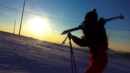 Silhouette of a woman with ski in winter mountains sunset close upの写真素材