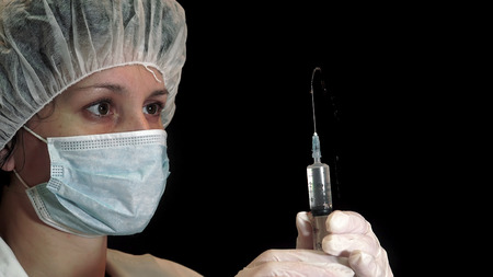 Nurse dispensing narcotics through a syringe against a black backgroundの写真素材