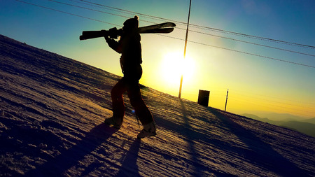Silhouette of a woman with ski in winter mountains sunset close upの写真素材