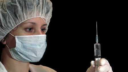 Nurse dispensing narcotics through a syringe against a black backgroundの写真素材