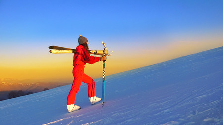 Skier climbing a snowy mountain at sunsetの写真素材