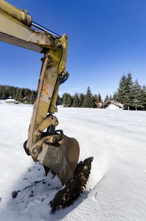 Close-up of a construction site excavator working on winter snowの写真素材