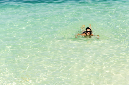 Woman with glassses floating and relaxing in turquoise waters at colorful tropical beachの写真素材