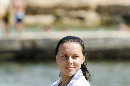 Portrait of happy girl smiling on the beach wrapped in a towelの写真素材