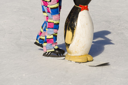 Closeup of young girl on the figure skates with learning penguin outdoor in sunny spring dayの写真素材