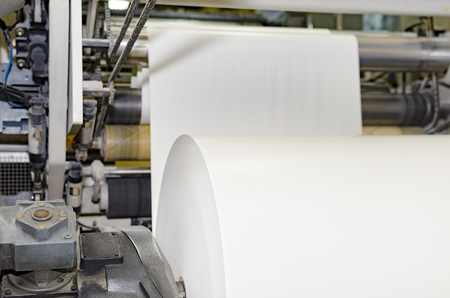 A large webset offset printing press running a long roll off paper over its rollers at high speedの写真素材
