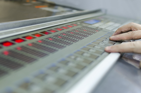 offset machine press print run at table, hands on fountain key control unit close-upの写真素材