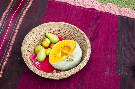 Ethno basket, fruit and old traditional red rugの写真素材