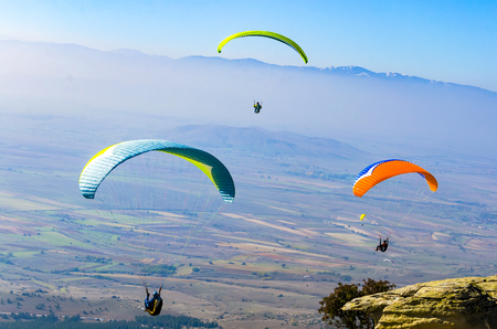 PRILEP, MACEDONIA - circa FEB, 2017: Three paraglider flies paraglider over the tops of the mountains in summer sunny dayのeditorial素材