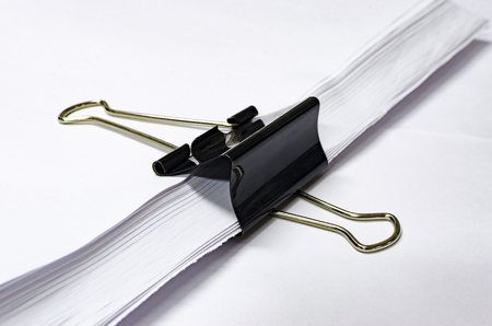 black paper clip holds stack of white print paper, office concept background, selective focusの写真素材