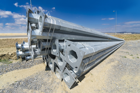 Stack of metal pipes at manufacturing plant construction site. Road construction light postsの写真素材