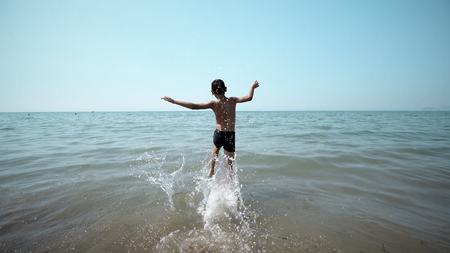 Happy boy getting int the sea water. Front cinematic steadicam viewの写真素材