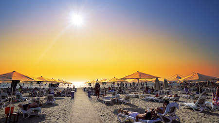 Beach chairs with umbrella on the beach at sunset. Cinematic steadicam shotのeditorial素材